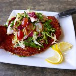 Schnitzel at the back abbey restaurant with salad on top.