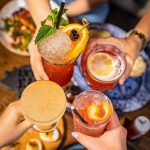 Four drinks clinking together over lunch at Gus's BBQ restaurant in Claremont