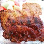 A rack of ribs with veggies behind from Wolfe's Kitchen and Deli.